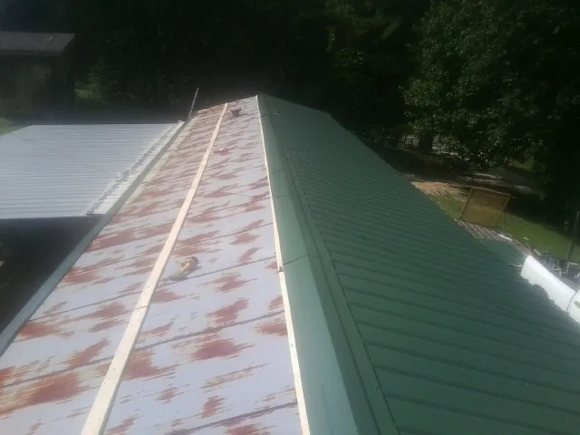 Old rusted panels beside newly installed green metal roofing — Wind Damage Roof Repair by Roofing Brothers in Chesterhill