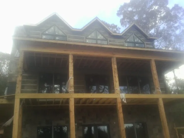 Dormers and porch framing on a large log home under construction — Roof Coating work by our crew in Chesterhill