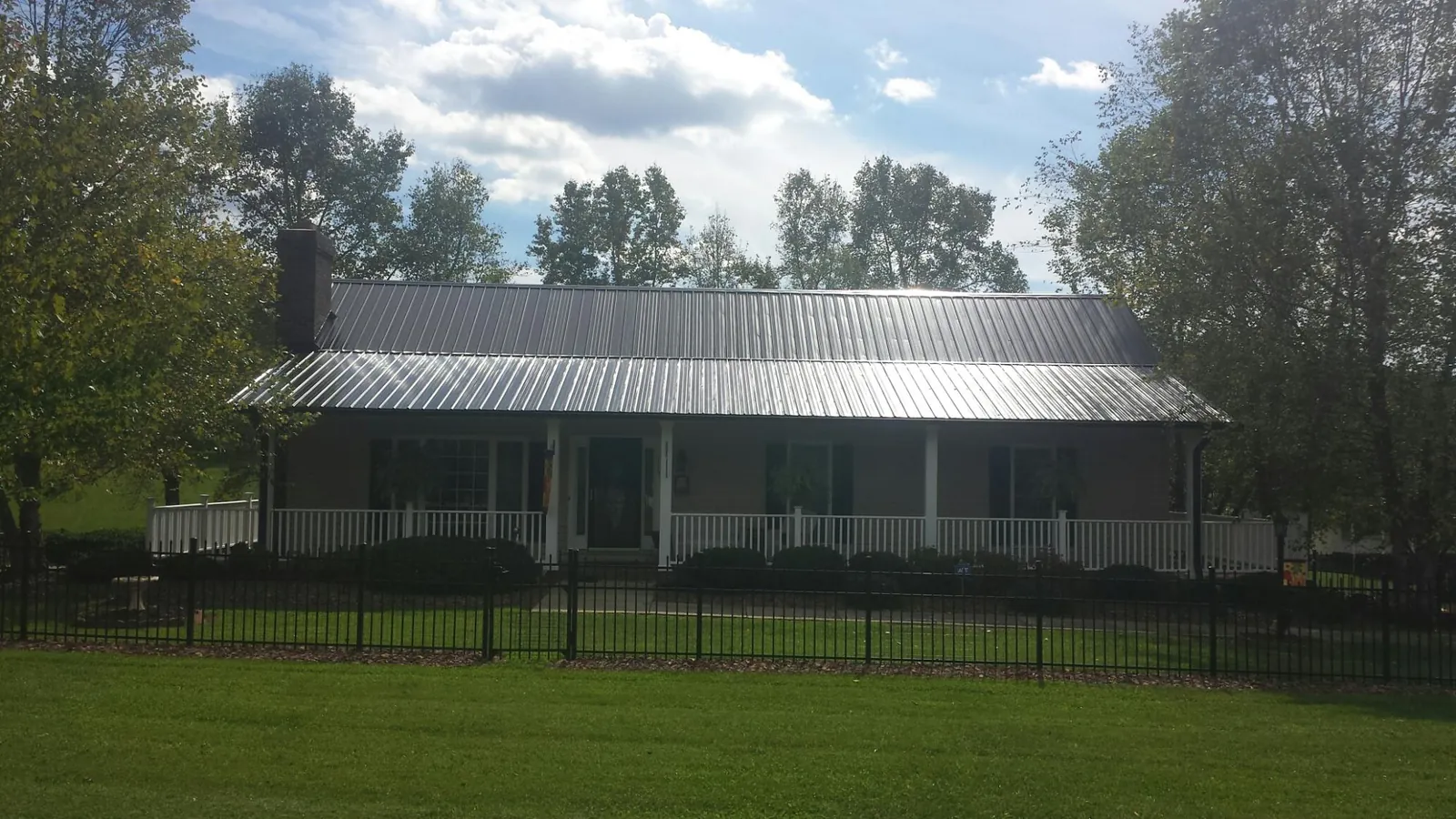 Gray metal roof on a brick ranch with a full width front porch — Gutter Guard Installation work by our crew in Chesterhill
