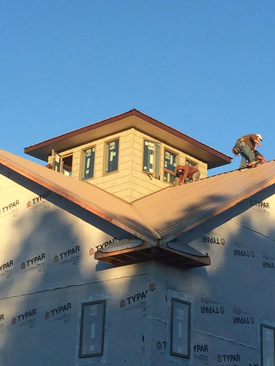Roofers working around a rooftop cupola on a new metal roof at sunset — Roof Waterproofing in Chesterhill by Roofing Brothers